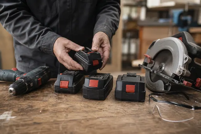 Batteries d’outillage sans fil de capacités différentes sur un établi en bois.