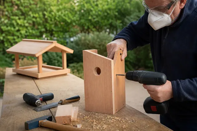 Fabrication d’un nichoir en bois brut sur un établi de jardin.