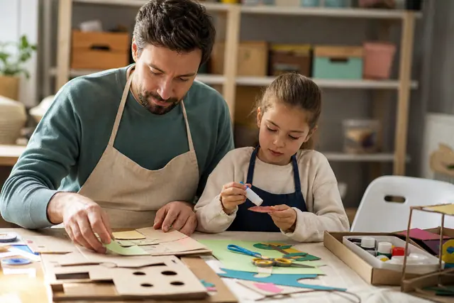 Parent et enfant réalisant un collage sur une table protégée et rangée.