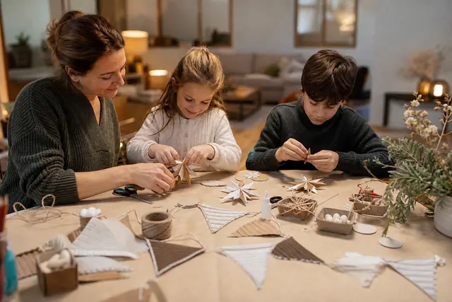 Enfants et adulte fabriquant des décorations de Noël en papier et carton.
