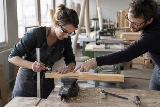 Débutante fixant une planche sur un établi lors d’un atelier bois.