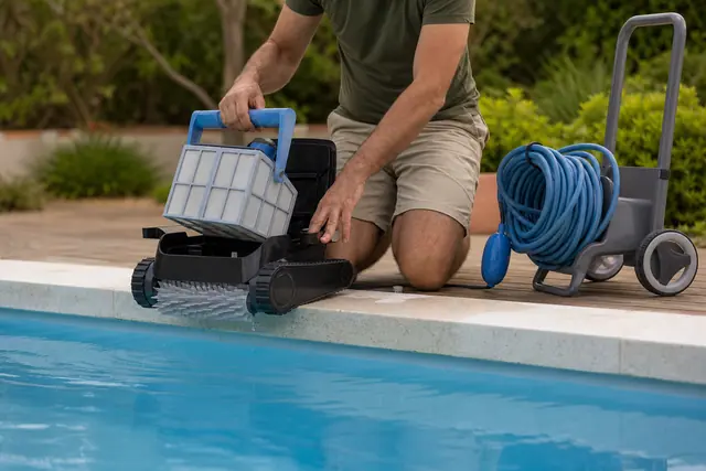 Robot électrique de piscine retiré après nettoyage sur une margelle en pierre.