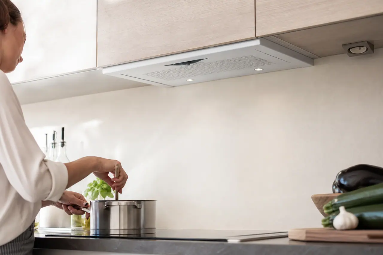 Hotte aspirante blanche installée au-dessus d'une plaque de cuisson dans une cuisine