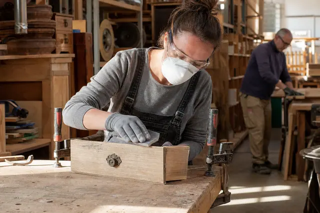 Atelier participatif de ressourcerie avec ponçage sécurisé d’un ancien tiroir en bois.