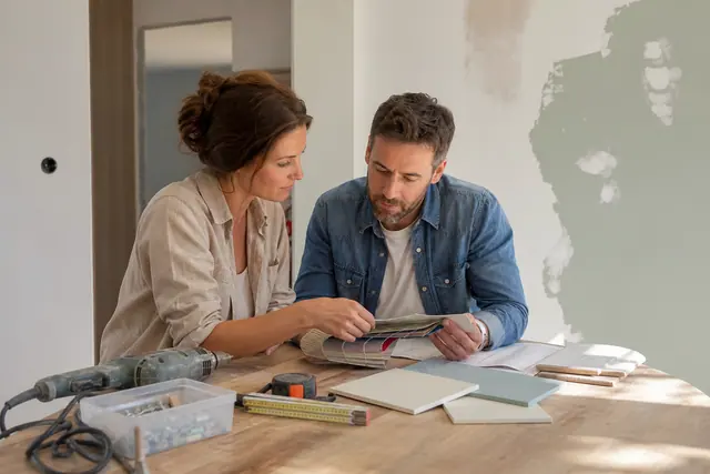 Couple comparant matériaux et outil réparé dans un salon en rénovation