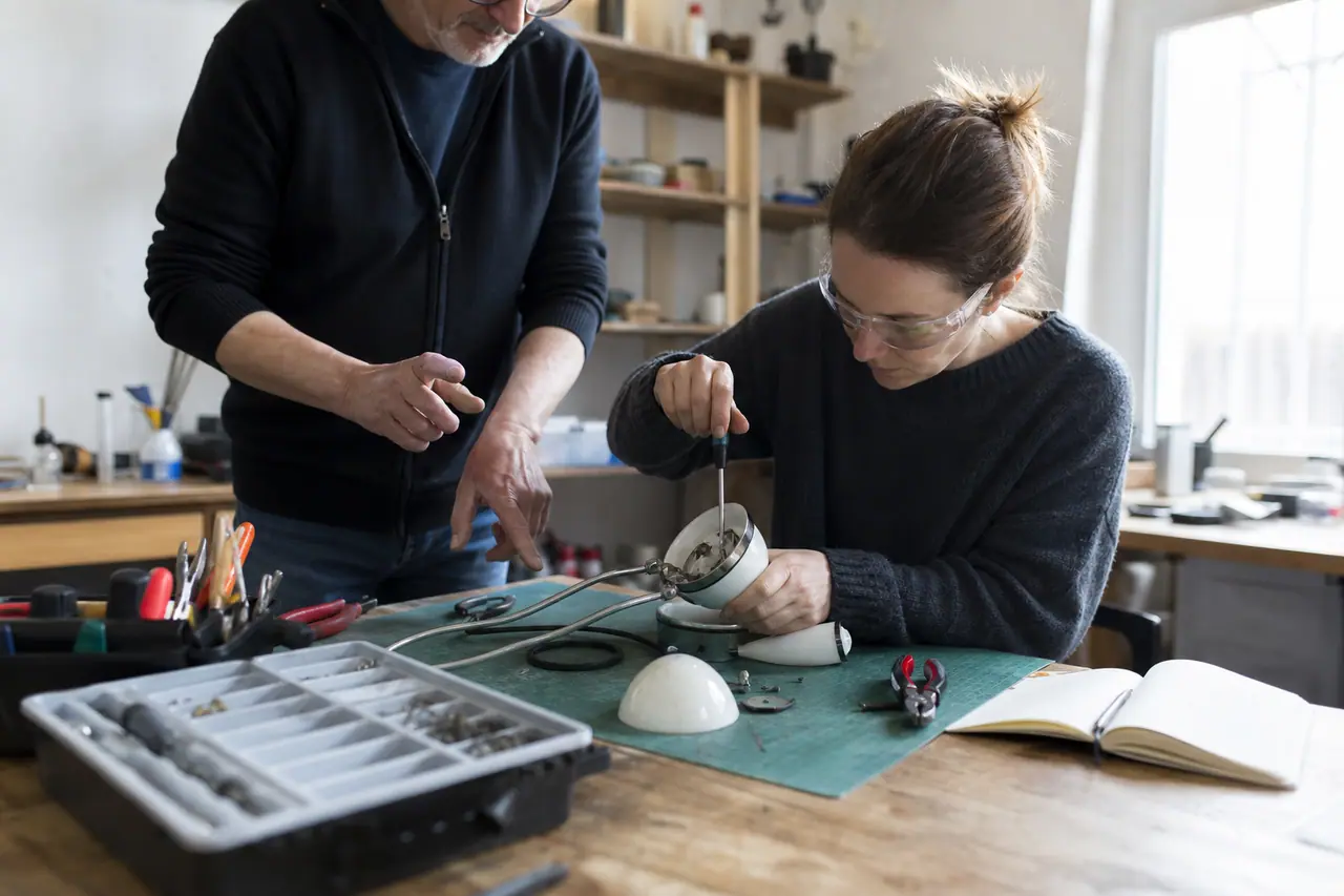 Débutante démontant une lampe débranchée avec l’aide d’un animateur d’atelier.