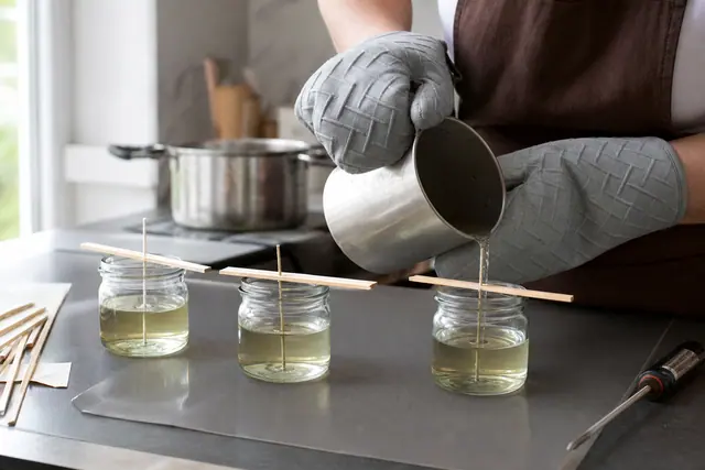 Coulage de cire parfumée dans des pots avec mèches centrées