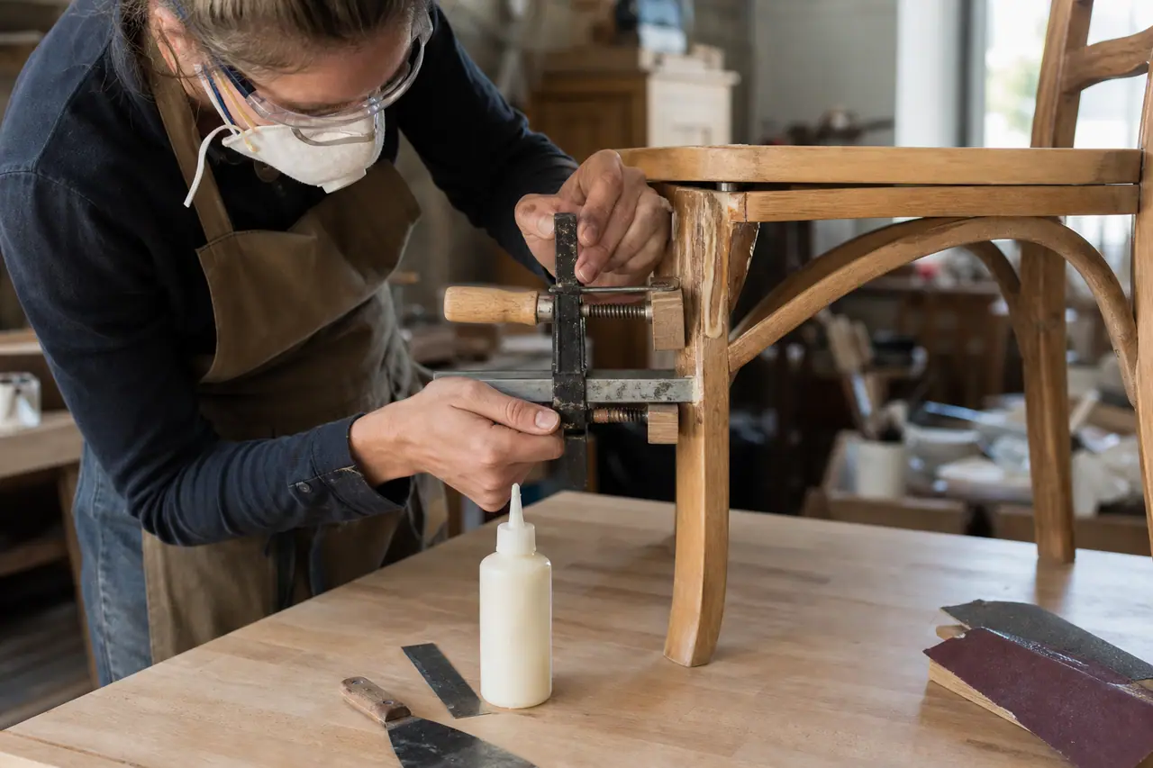 Réparation d’un assemblage de chaise en bois avec serre-joints et cales de protection.