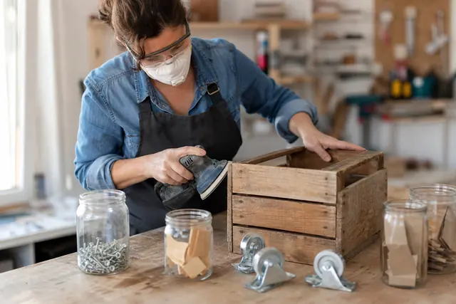 Caisse en bois récupérée préparée avec bocaux et roulettes sur un établi.