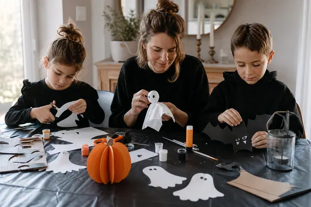 Enfants réalisant des fantômes en papier sur une table protégée