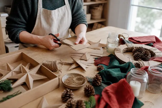 Créations de Noël en carton, tissu et pommes de pin sur une table.