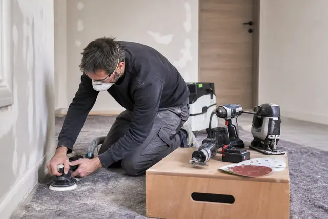 Quatre outils sans fil compacts préparés pour rénover un appartement protégé de la poussière.