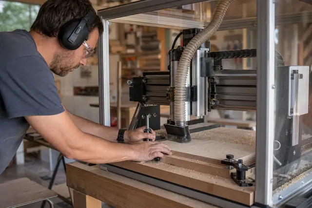 Opérateur réglant une fraiseuse CNC dans un atelier domestique propre et équipé.