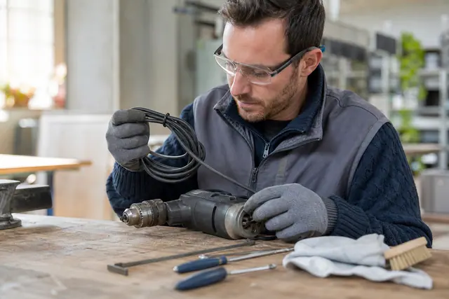 Bricoleur examinant le câble et le mandrin d’une perceuse d’occasion