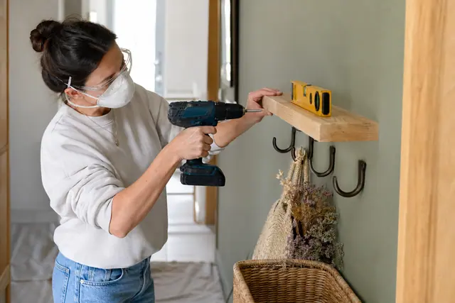 Bricoleuse installant une étagère claire dans une entrée soigneusement rangée