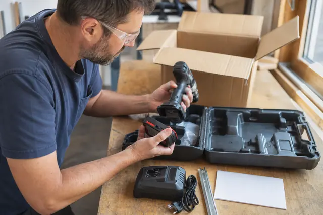 Bricoleur vérifiant un outil sans fil et ses accessoires dans un coffret ouvert.
