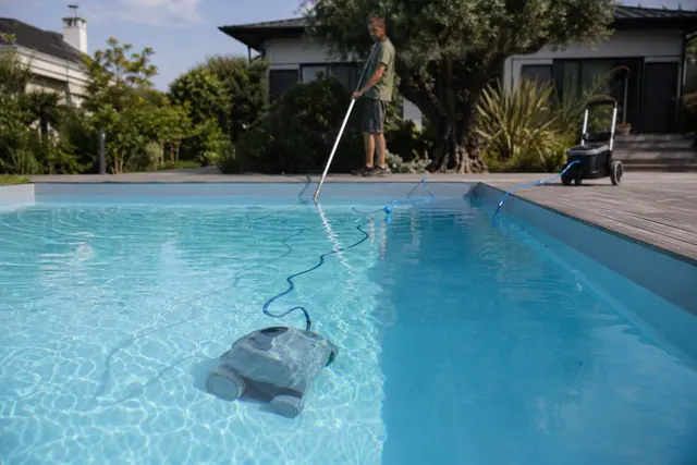 Robot électrique nettoyant le fond d’une piscine à liner depuis une terrasse.