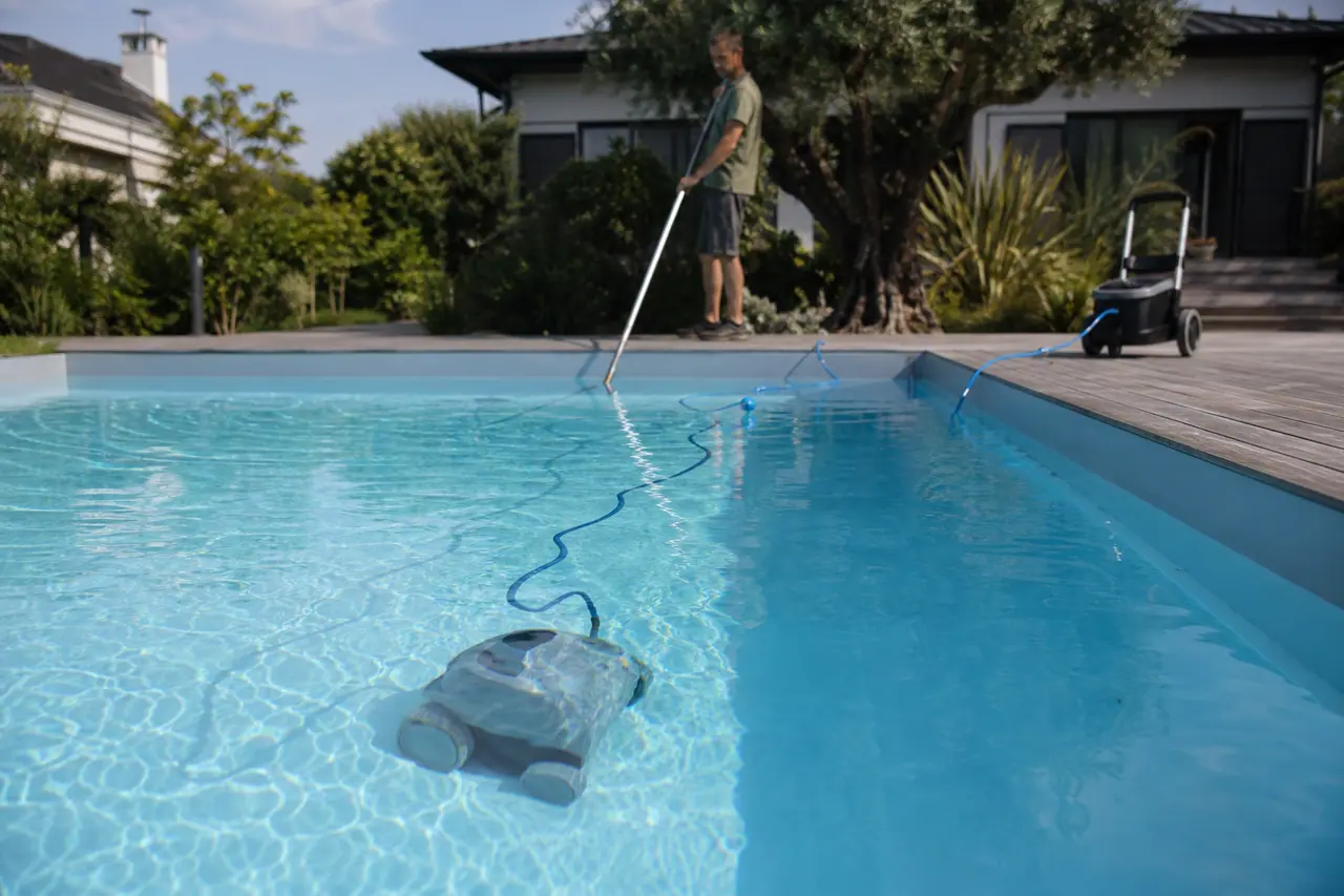 Robot électrique nettoyant le fond d’une piscine à liner depuis une terrasse.