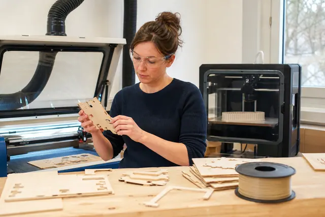 Atelier encadré avec imprimante 3D et découpeuse laser fermée sur établi.