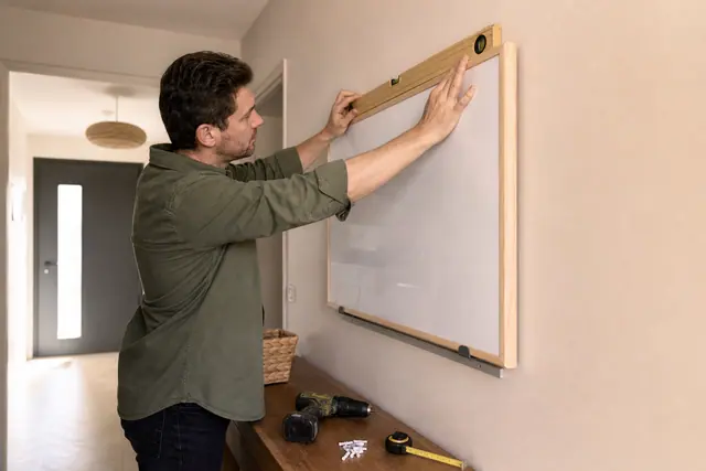 Tableau magnétique fixé droit sur un mur avec rail discret et niveau à bulle.