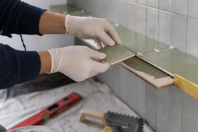 Pose de petits carreaux sur une tablette murale avec profilé de finition.