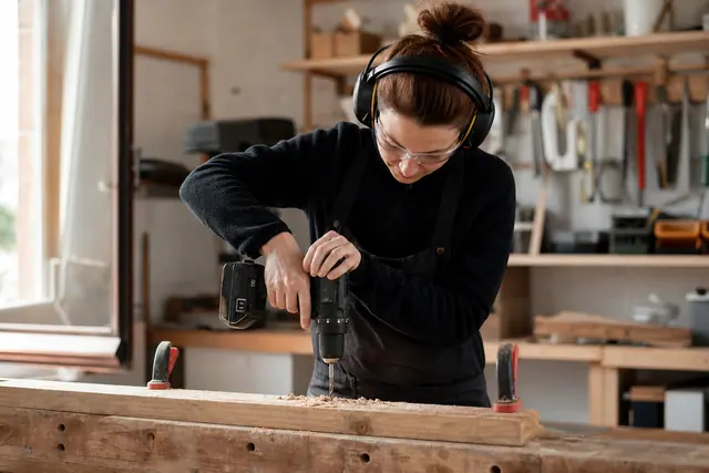 Bricoleuse équipée testant une perceuse sur une planche solidement serrée.