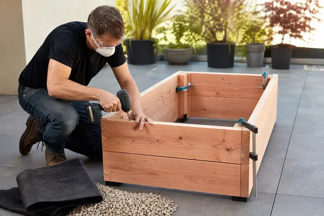 Assemblage vissé d’une jardinière en bois sur une terrasse avec fond drainant.