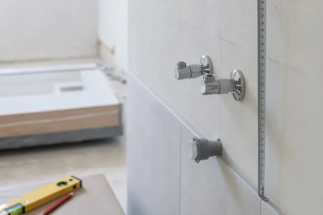 Attentes d'eau et évacuation sortant d'un mur de salle de bain avant la pose du meuble vasque