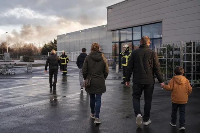 Clients évacuant calmement un magasin de bricolage pendant l’intervention des pompiers.