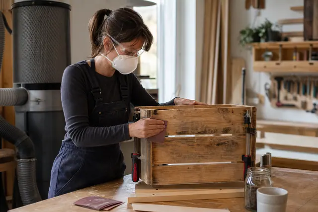 Bricoleuse ponçant une caisse en bois recyclée dans un atelier lumineux