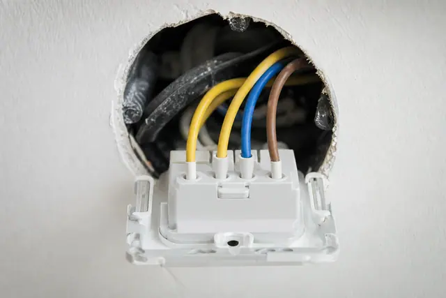 Permutateur électrique blanc avec quatre bornes de navette raccordé dans une boîte d'encastrement
