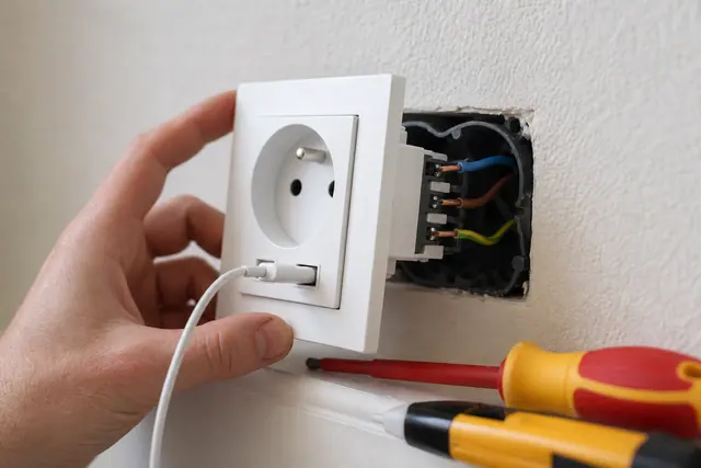 Prise murale avec ports USB intégrés en cours de raccordement dans un boîtier électrique
