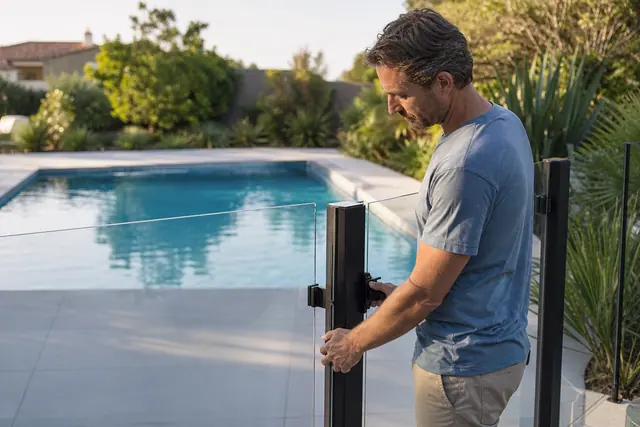 Barrière transparente verrouillée autour d’une piscine familiale dans un jardin contemporain