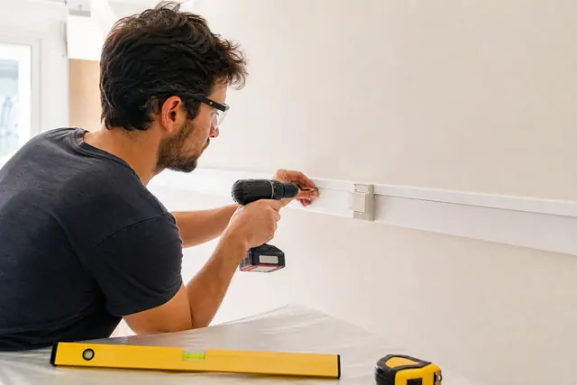 Particulier fixant un module clipsable sur un mur peint de bureau.