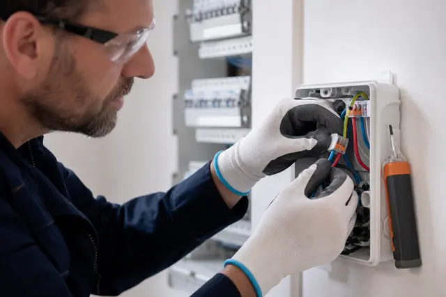 Électricien contrôlant un raccordement clipsable dans une boîte de dérivation accessible.