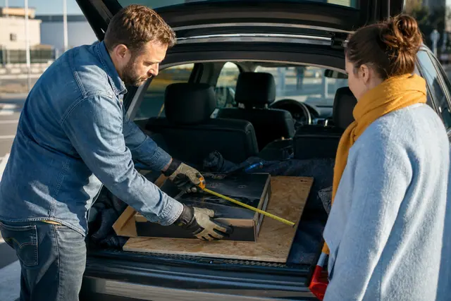 Client mesurant un panneau avant de charger ses achats de bricolage en voiture.