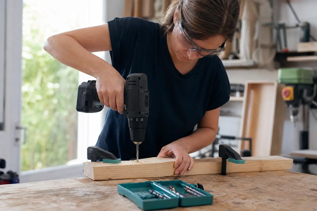 Perceuse-visseuse compacte utilisée sur une planche de pin solidement bridée.