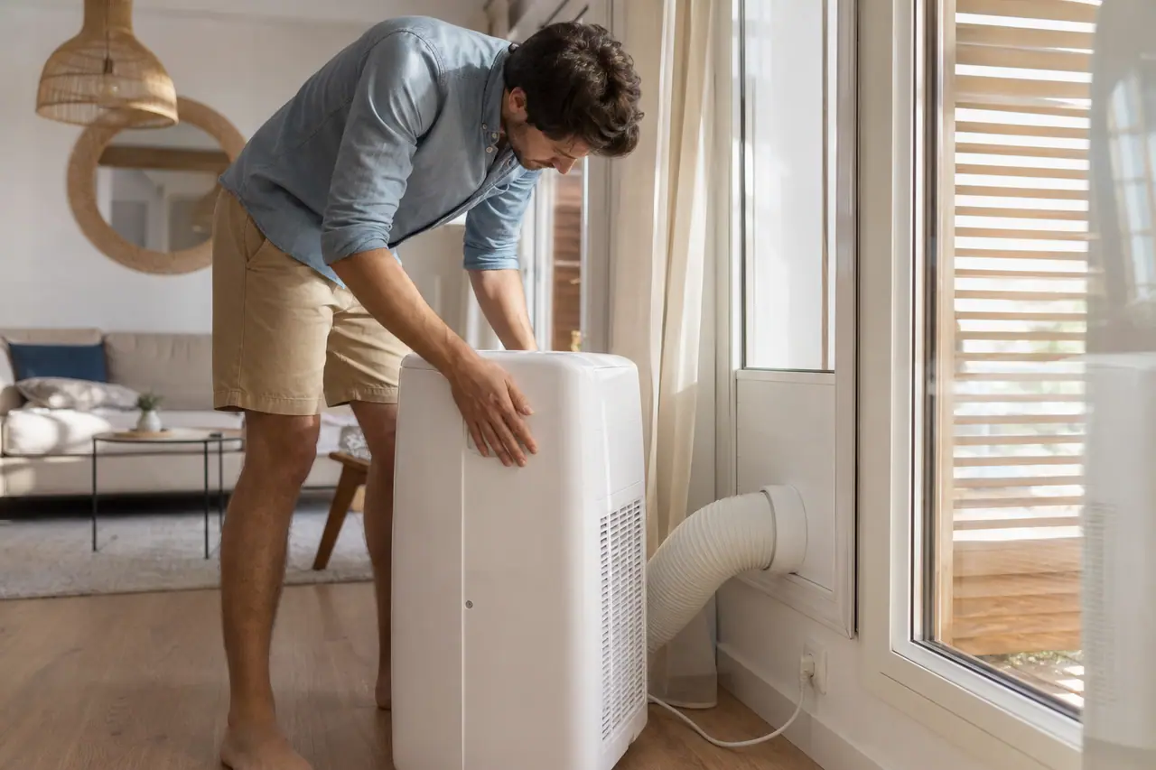 Climatiseur mobile correctement raccordé à une fenêtre étanchée dans un séjour lumineux.