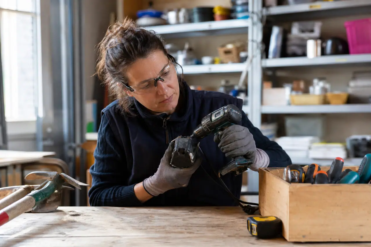 Bricoleuse contrôlant une perceuse d’occasion sur l’établi d’une ressourcerie.