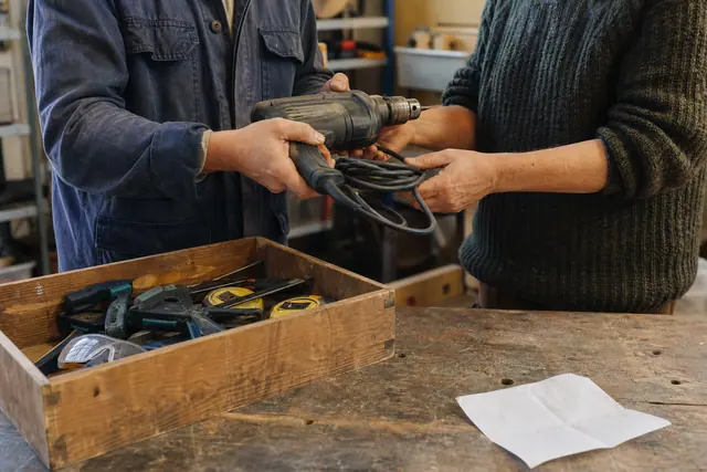 Voisins contrôlant une perceuse et une caisse d’outils dans un atelier partagé