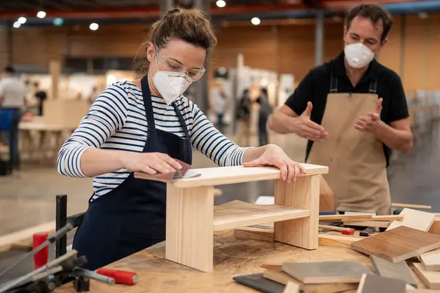 Participante ponçant une petite étagère en bois lors d’un atelier DIY encadré.