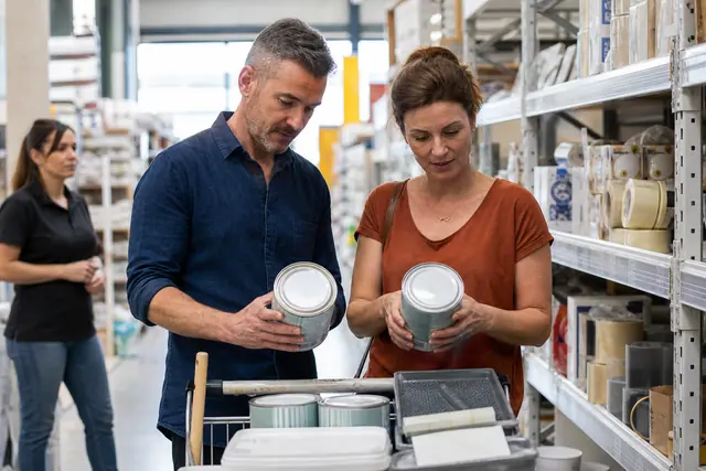 Clients comparant des produits dans une allée de magasin de bricolage.
