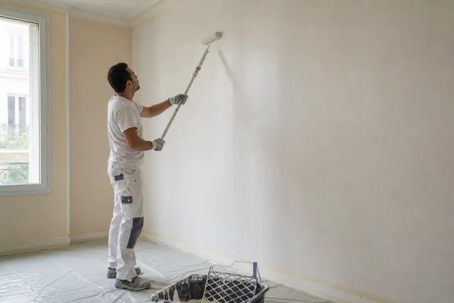 Application régulière de peinture au rouleau sur un mur intérieur préparé.