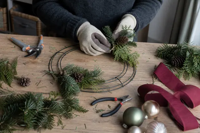 Montage d’une couronne végétale sur un cintre métallique avec fil de fleuriste.