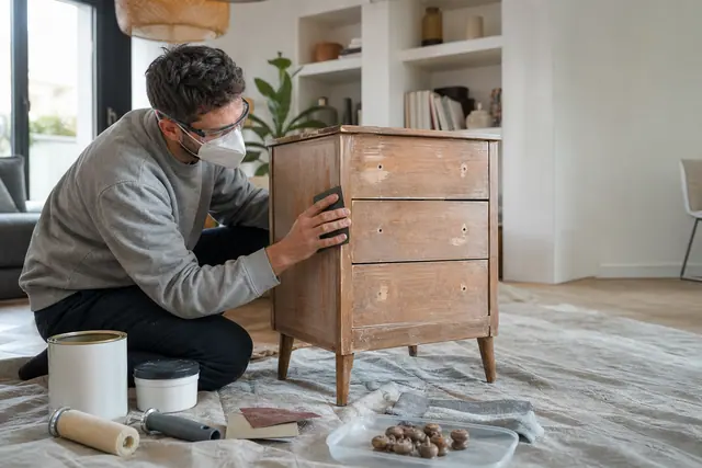 Personne préparant une commode en bois avant de la repeindre