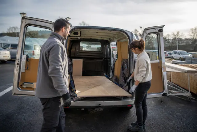 Retrait de panneau de bois dans un utilitaire sur un parking de bricolage.
