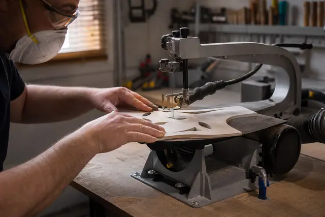 Bricoleur équipé découpant un motif ajouré dans du contreplaqué avec une scie fixe.