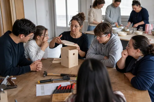 Animatrice guidant un groupe dans un atelier associatif de bricolage sécurisé.