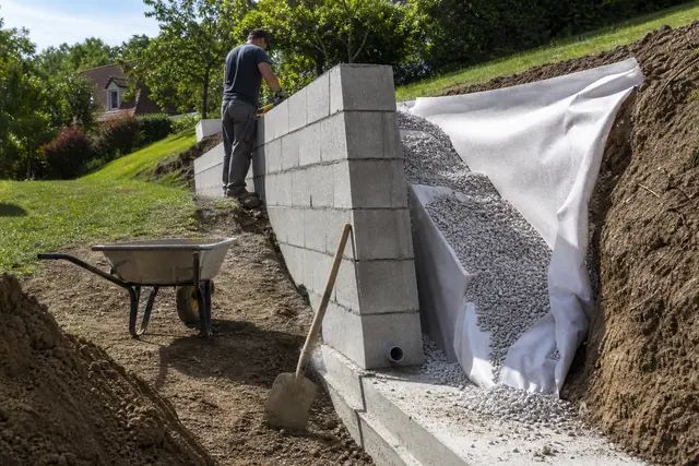 Mur de soutènement en parpaing avec drainage en gravier visible avant remblaiement final