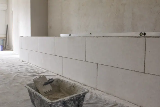 Cloison en carreaux de plâtre montée à mi-hauteur, joints décalés, niveau posé dessus